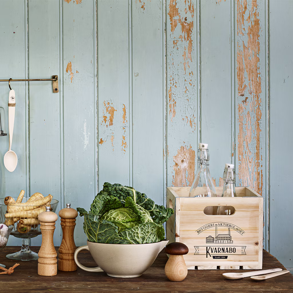 Rustykalna kuchnia ze świeżą kapustą liściastą, drewnianymi młynkami do pieprzu, dziadkiem do orzechów Grzybek, szklaną skrzynką na butelki, niebieskimi ścianami w stylu vintage.